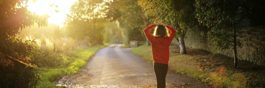 Woman in orange long sleeve shirt stretches before morning jog